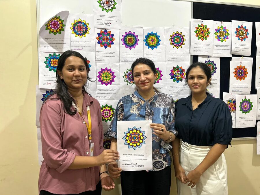 Women holding their finished mandala artwork, smiling