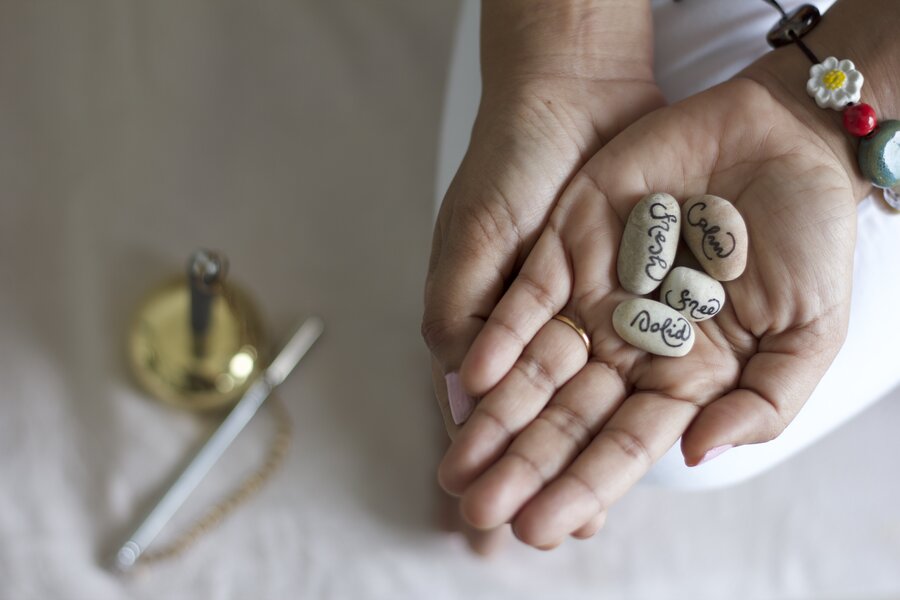 Cupped hands holding stones inscribed with words: fresh, calm, free, solid