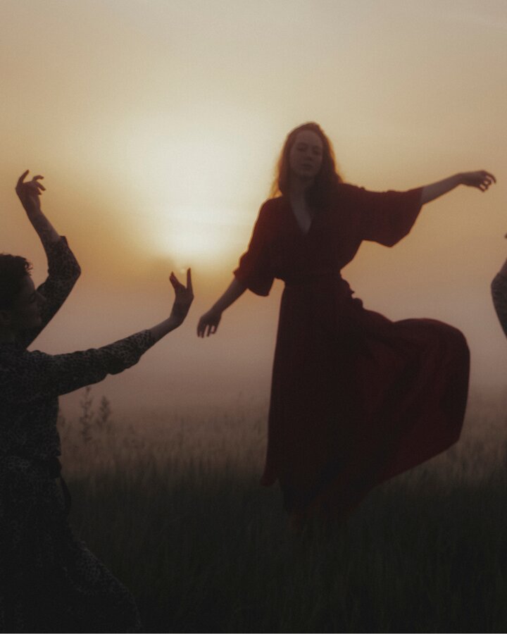 Women dancing freely at sunset, arms raised