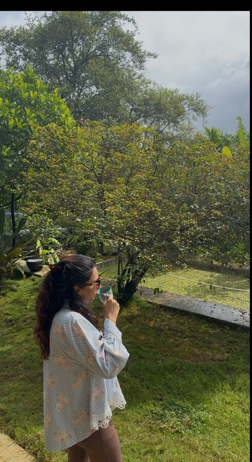 A woman pausing quietly outdoors with a warm cup