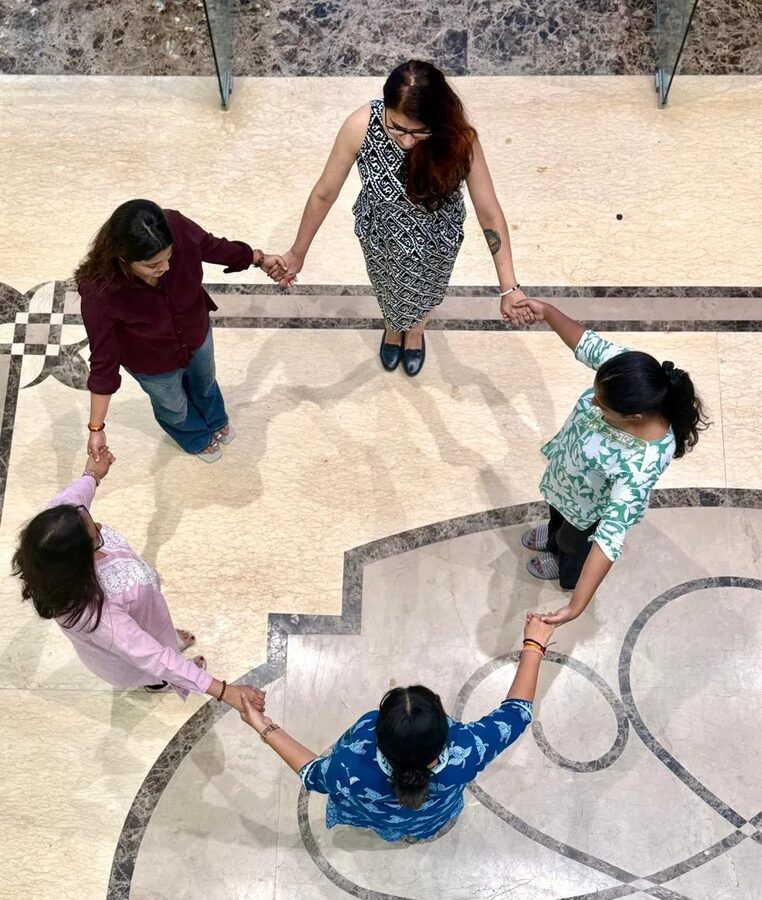 Women holding hands together in a circle, overhead view